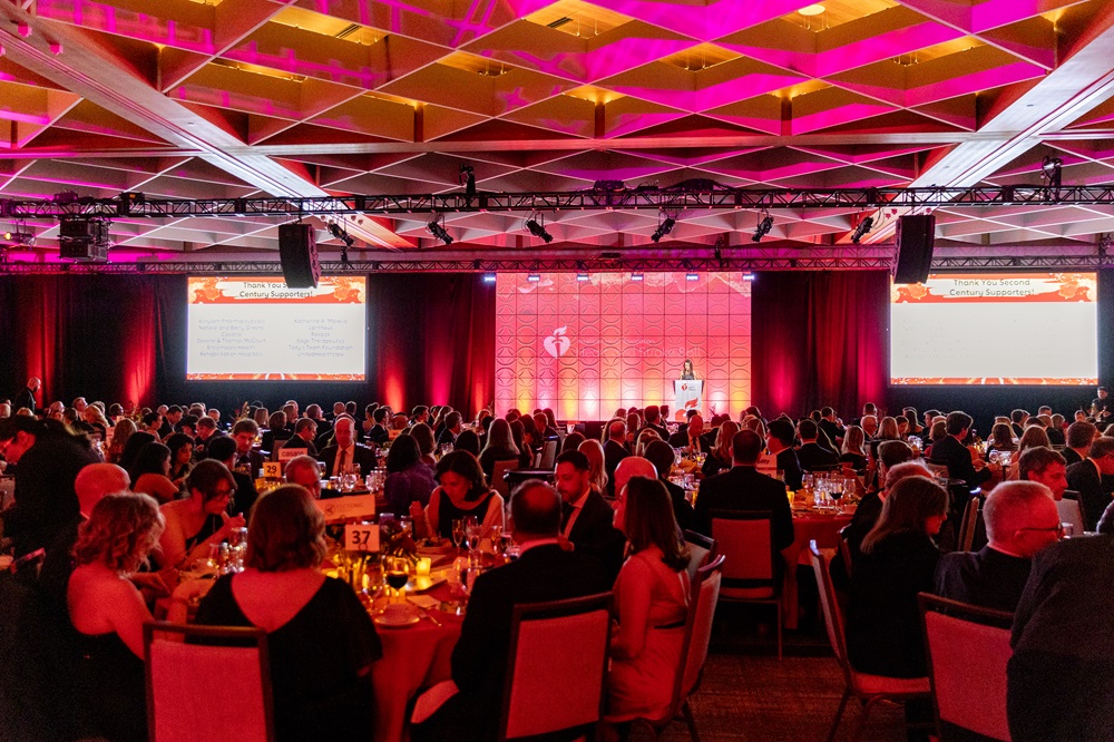 Wide view of ballroom with all tables full of seated guests.